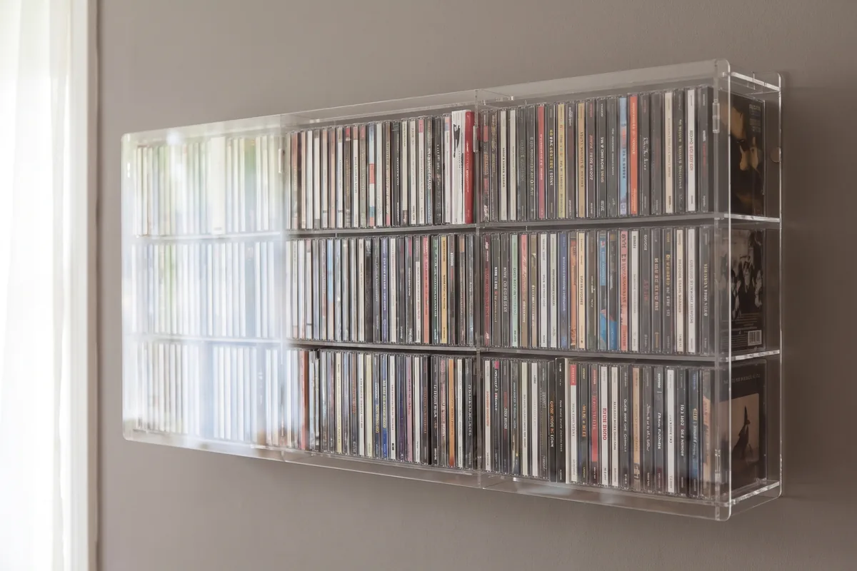 CD/DVD-Maßregal aus Acryl an der Wand, gefüllt mit CDs