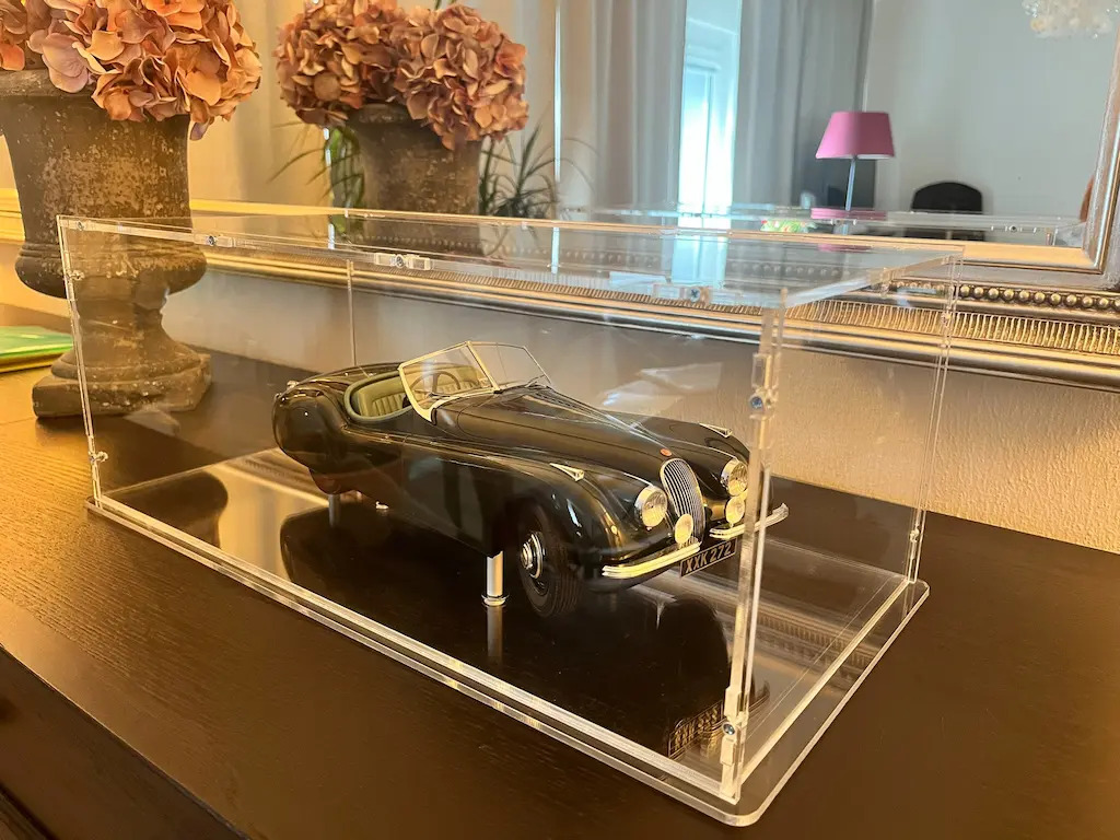Sora-Maßhaube über schwarzem Jaguar-Roadster als Modellauto, präsentiert auf dunkler Sockelplatte mit Spiegelung