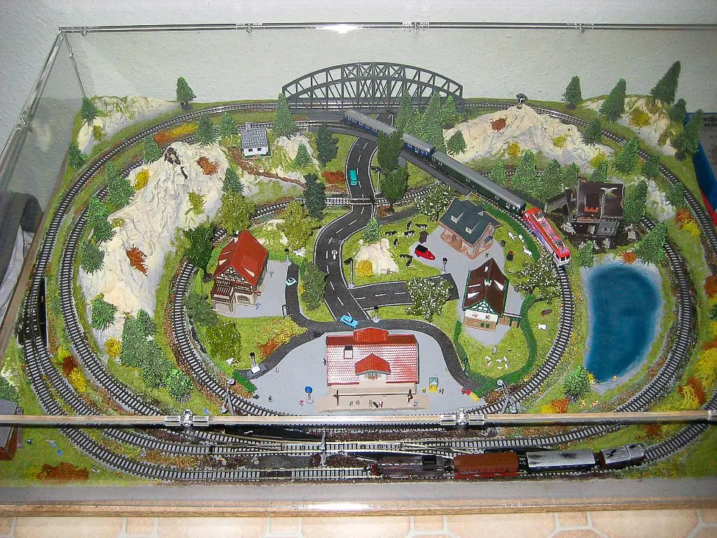 Große Sora-Maßhaube über kompletter Modelleisenbahn-Landschaft mit Brücke, Bergen, Tunneln, See und Bahnhof